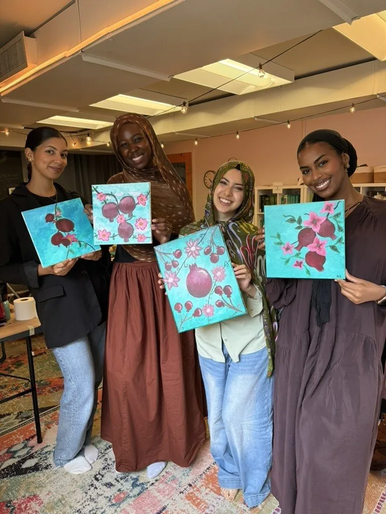 Four guests standing together with their finished canvases.