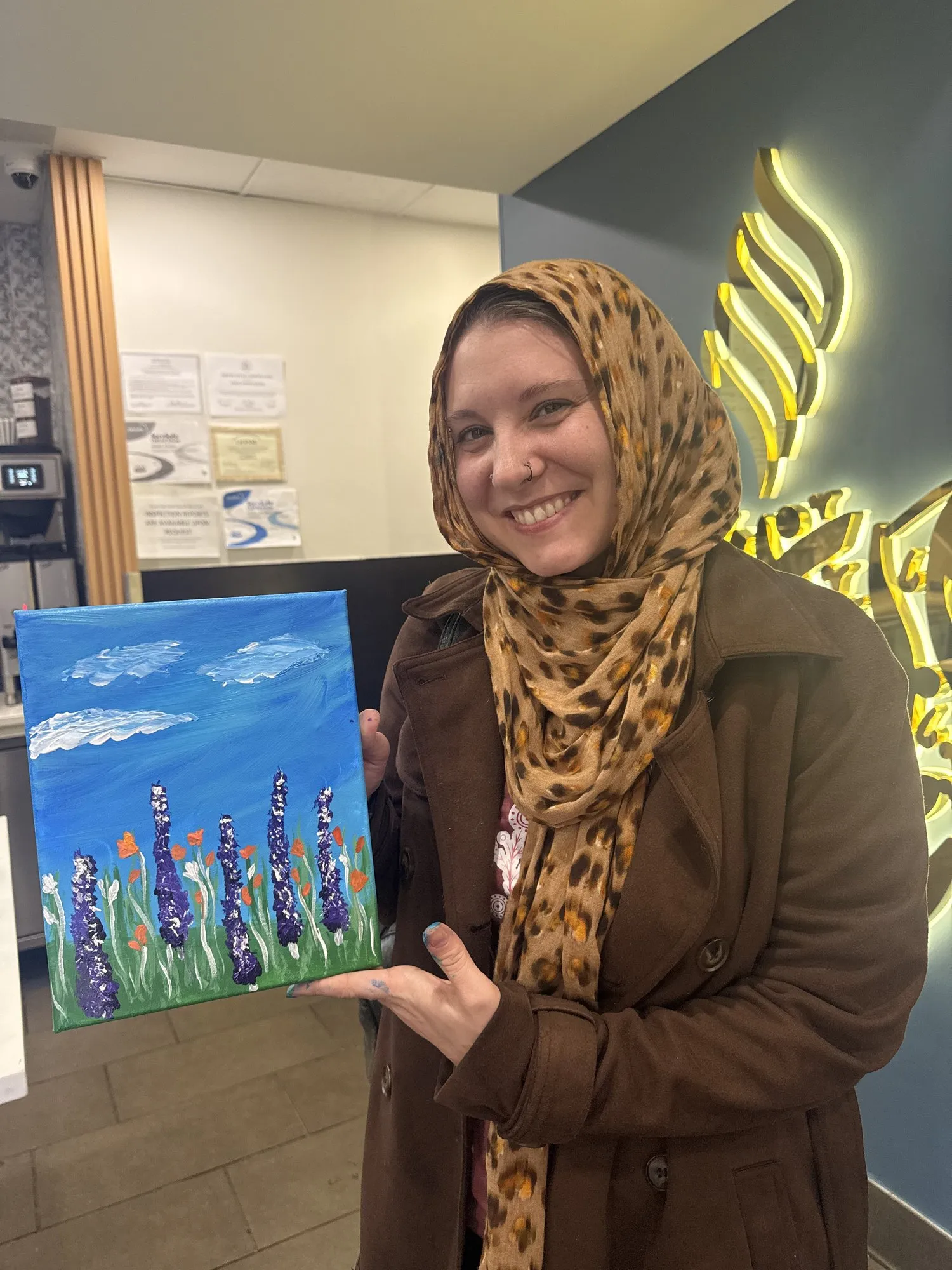 A guest holding a painting of purple flowers in a field.