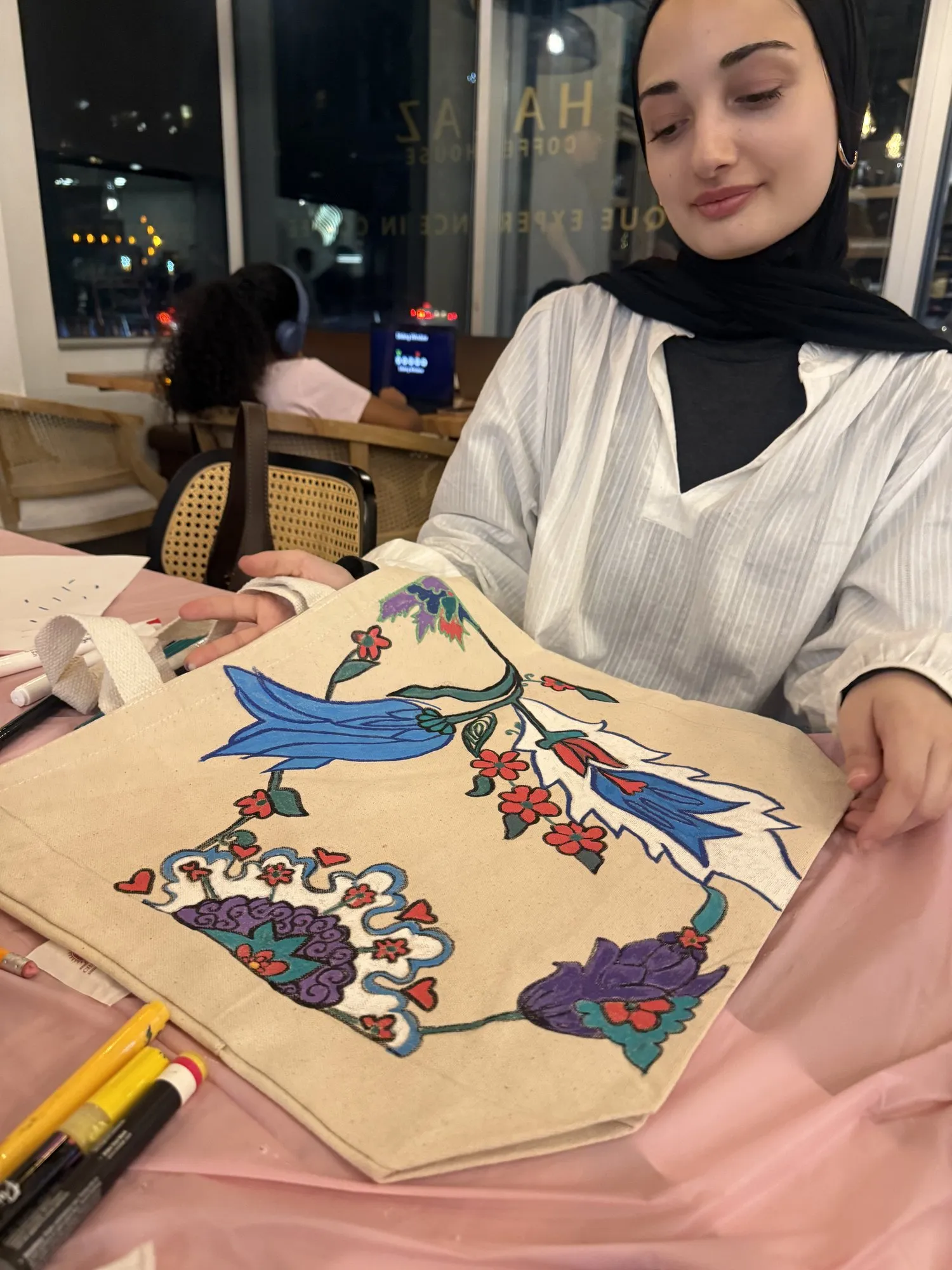 A guest showing a tote bag she painted with blue birds and red flowers.